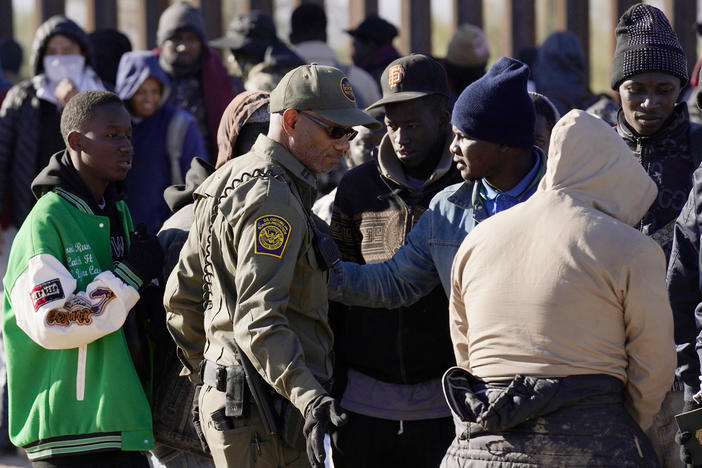 A group of migrants gather along the border after breaking through gaps in the border wall Tuesday, Dec. 5, 2023, in Lukeville, Ariz.