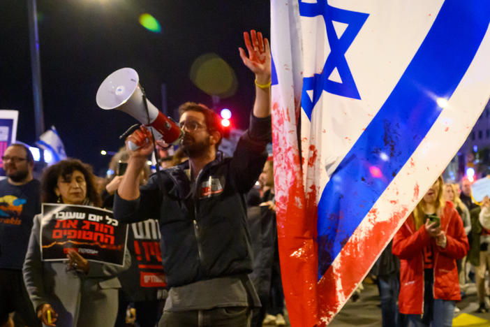 A protester with red paint on his hand marches through the streets after demonstrating outside the Israel Defense Forces headquarters on Friday in Tel Aviv, Israel. Earlier, the IDF had said its forces accidentally killed three hostages being held in Gaza when it mistakenly identified them as potential threats.