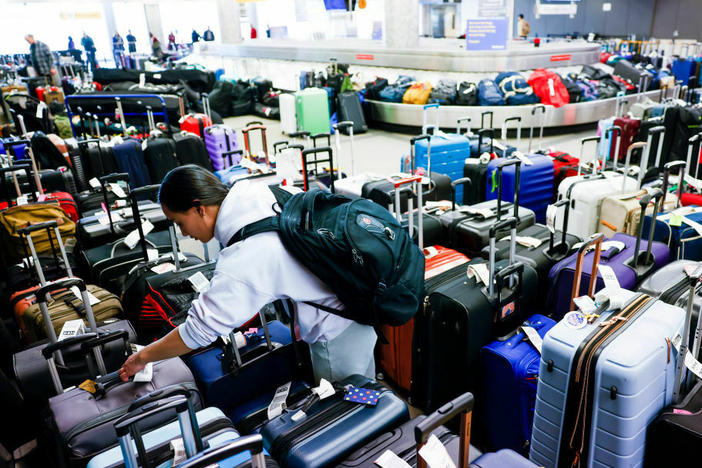 Pristine Floyde searches for a friend's suitcase in a baggage holding area for Southwest Airlines at Denver International Airport in December 2022.