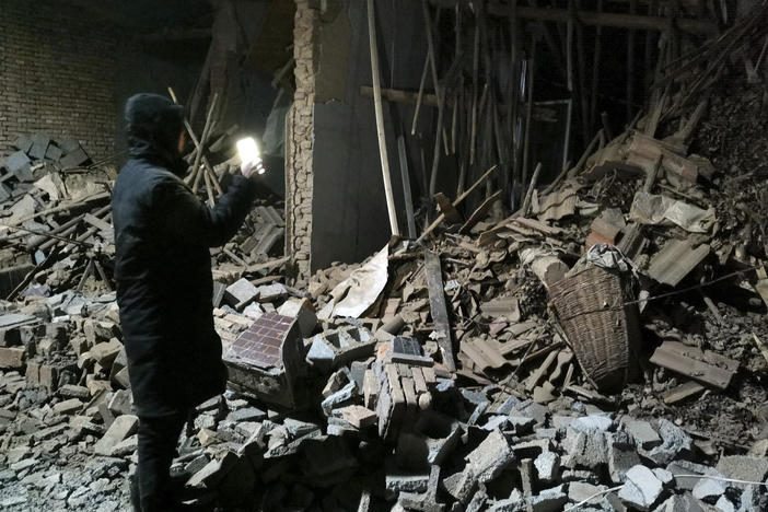 A government worker looks at the debris of a house brought down in the earthquake in Jishishan county in northwest China's Gansu province Tuesday, Dec. 19, 2023.