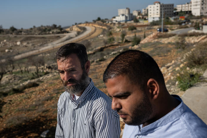 Palestinian farmers Naser El Khatib and Thaer El Taher stand on land filled with their olive trees at the edge of Beitunia, across from an area controlled by Israel in the occupied West Bank, on Dec. 2.