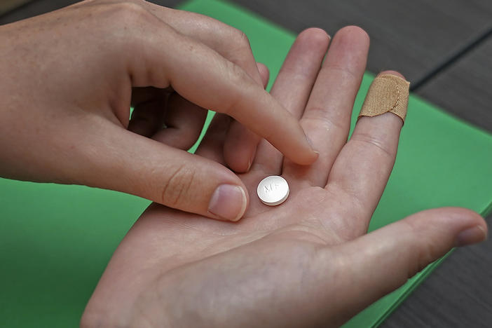 A patient prepares to take the first of two combination pills, mifepristone, for a medication abortion during a visit to a clinic in Kansas City, Kan., on Oct. 12, 2022.