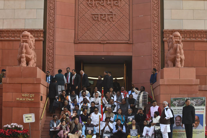 Indian lawmakers sit on the stairs of the Parliament building in protest against the suspension of lawmakers, in New Delhi, Tuesday. Dozens of opposition lawmakers were suspended on Monday after they held a protest demanding the home minister give a statement on the security breach in parliament earlier this month.
