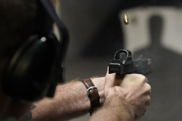 A man fires his pistol at an indoor shooting range during a qualification course to renew his Carry Concealed handgun permit at the Placer Sporting Club, July 1, 2022, in Roseville, Calif.