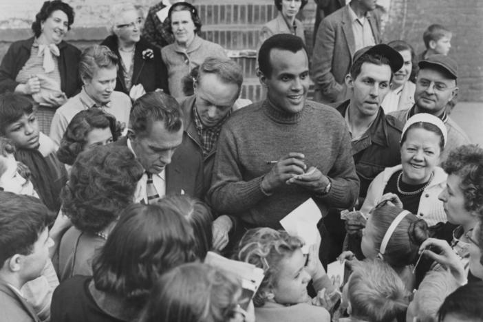 Harry Belafonte, alongside Ed Sullivan, signs autographs for fans outside CBS Studio 50 in New York City, circa 1955.