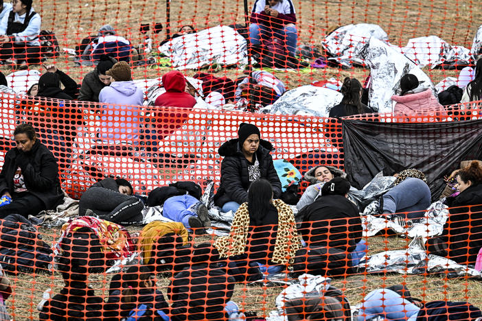 Immigrants wait to be processed after they crossed the border into the U.S. in Eagle Pass, Texas, on Dec. 22. Eleven states and D.C. offer taxpayer-funded health insurance to some immigrants without legal status.