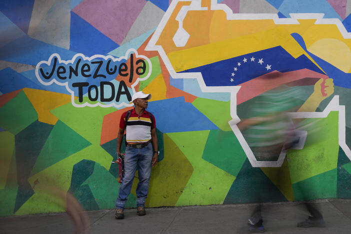 A man sells phone cables in front of a mural of the Venezuelan map with the Essequibo territory included in the Petare neighborhood of Caracas, Venezuela, on Dec. 11.