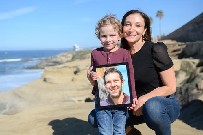 Laura Keenan and her son, Evan, hold a photo of her late husband Matt Keenan, who was killed while riding his bike in San Diego in 2021.
