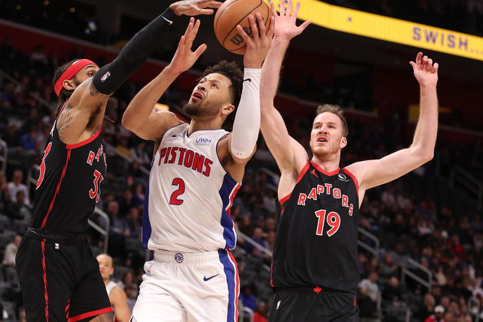 Cade Cunningham #2 of the Detroit Pistons drives to the basket between Gary Trent Jr. #33 and Jakob Poeltl #19 of the Toronto Raptors during the first half at Little Caesars Arena on Saturday in Detroit.