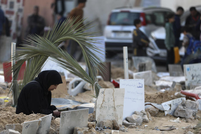 Palestinians visit the graves of people killed in an Israeli bombardment of the Gaza Strip and buried inside the Shifa Hospital grounds in Gaza City, on Sunday, Dec. 31, 2023.