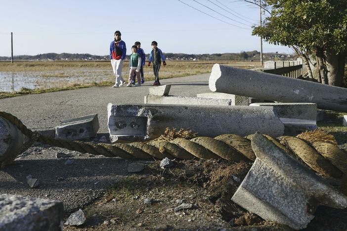 People walk by a torii gate damaged by an earthquake at a shrine in Hakui, Ishikawa prefecture, Japan Tuesday, Jan. 2, 2024.