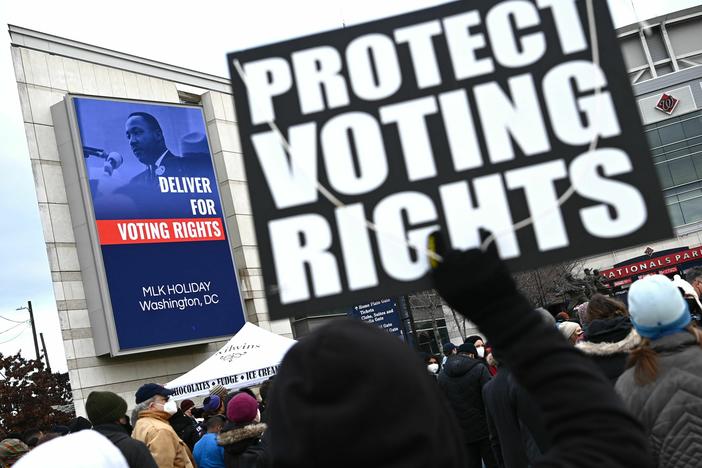 A participant in the annual Martin Luther King Jr. Memorial Peace Walk in Washington, D.C., holds a sign that says "PROTECT VOTING RIGHTS" in 2022.