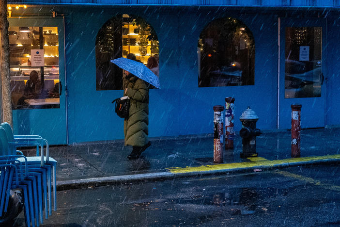People walk through lower Manhattan as it snows on Saturday in New York City.