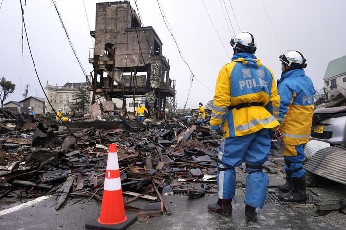 Police officers search for  victims in debris of damaged and burnt buildings in Wajima northwest of Tokyo, on Sunday, Jan. 7, 2024. Monday's temblor decimated houses, twisted and scarred roads and scattered boats like toys in the waters, and prompted tsunami warnings.