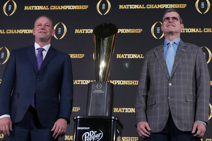 Washington head coach Kalen DeBoer, left, and Michigan head coach Jim Harbaugh pose with the trophy after a news conference ahead of the national championship NCAA College Football Playoff game between Washington and Michigan on Sunday, Jan. 7, 2024, in Houston. The game will be played Monday.