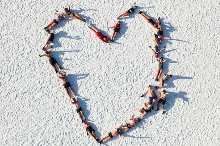 Lovers of winter swimming draw a heart as they pose lying on the icy beach after swimming in the icy water of the Baltic Sea in Gdansk, Poland, on Valentine's Day, Feb. 14, 2021.