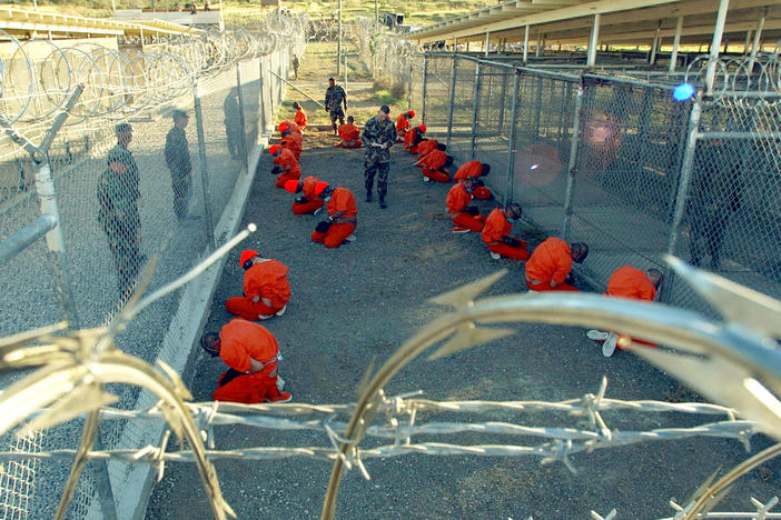 In this handout photo provided by the U.S. Navy, U.S. Military Police guard detainees in orange jumpsuits on Jan. 11, 2002 at Guantánamo Bay, Cuba.