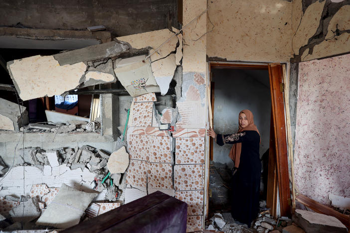A woman stands in her damaged house in Rafah, in the southern Gaza Strip, on Friday, following Israeli bombardment amid continuing battles between Israel and the Palestinian militant group Hamas.