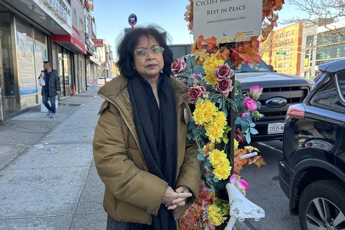 Lizi Rahman puts silk flowers on the white-painted "ghost" bicycle that marks the spot on Queens Boulevard where her son Asif was killed in 2008.