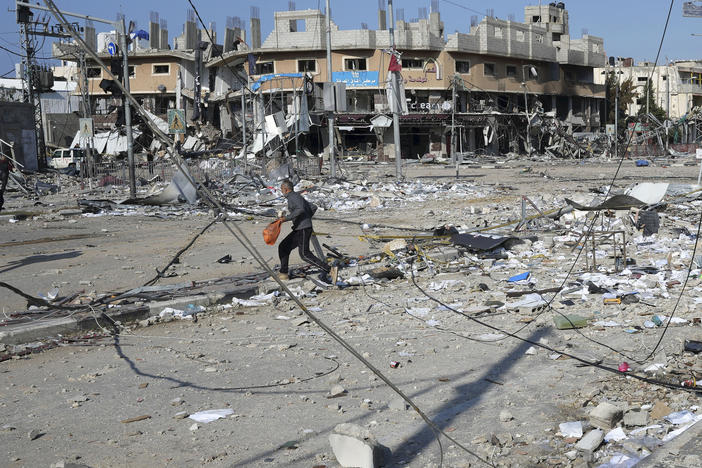 Palestinians walk through destruction by an Israeli bombardment in the Nusseirat refugee camp in Gaza on Tuesday, Jan. 16, 2024.