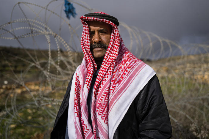 Sakher Abu Dahouk in front of the razor wire of the separation barrier that surrounds his land in Beit Hanina Al-Balad in the Israeli-occupied West Bank. His extended family has moved several times since 1948, as Israel seized territory in subsequent wars, redrew boundaries and built more Jewish settlements. "We still have deeds to our land," in what's now southern Israel, he says.