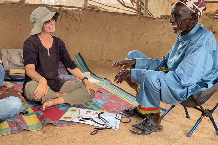 Anthropologist Carla Handley, center, meets with Wario Bala, right, to present the results of a DNA study she conducted seven years ago in his community in northern Kenya.