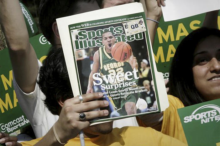 A George Mason University fan holds up the cover of a <em>Sports Illustrated</em> magazine at a send-off for the university's team on March 29, 2006, in Fairfax, Virginia. The union representing the magazine's staff said that SI's publisher plans to cut "a significant number, possibly all" of its union-represented staff.