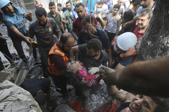 Palestinians rescue a child from under the rubble after Israeli airstrikes in Gaza City, Gaza Strip, on Oct. 18, 2023.
