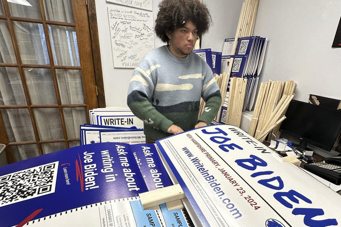 Malikiah Guillory, 19, stacks yard signs in Hooksett, N.H., on Wednesday, urging voters to write in President Biden's name on the Democratic primary ballot. Biden is skipping the New Hampshire primary because it didn't comply with party rules.