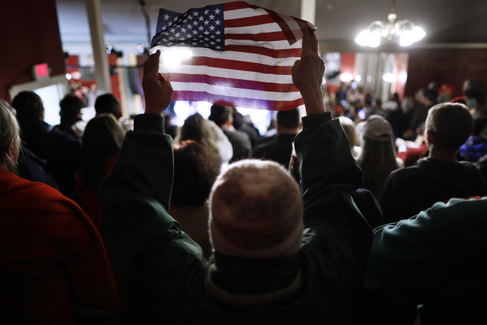 A woman holds up a small U.S. flag during a campaign rally by GOP presidential candidate and former President Donald Trump at the Rochester Opera House on Jan. 21 in Rochester, N.H.