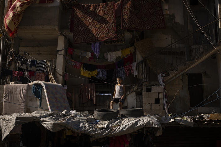 A Lebanese boy stands atop the roof of a crumbling house within the bustling streets of the Shatila refugee camp in Beirut.