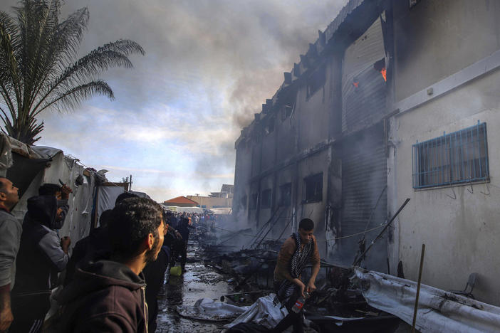 Palestinians try to extinguish a fire at a building of an UNRWA vocational training center that displaced people use as a shelter on Jan. 24, 2024.