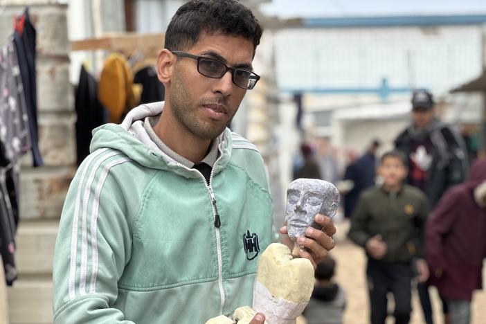 Yousef al-Hindi holds a puppet, also named Yousef, that he created using materials found in his camp in Rafah.