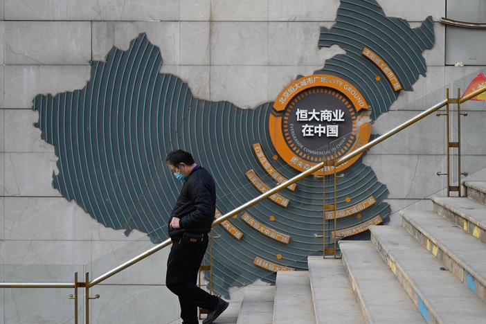 At a partially operating Evergrande commercial complex in Beijing on Monday, a man walks past a map of China that shows Evergrande's commercial complexes throughout the country. Evergrande was once listed as the world's most valuable real estate company, but on Monday, a Hong Kong court ordered it to be liquidated.