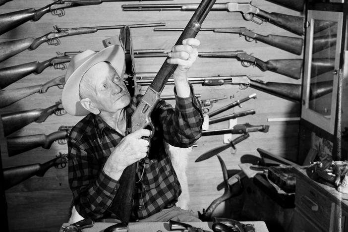 C.J. Hurst of West Covina, Calif., holds up a .44-caliber rimfire Model 66 Winchester rifle as he poses with his collection of about 600 antique guns in 1952.