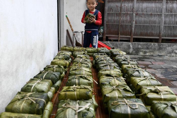 A boy looks at "Banh Chung" or traditional Vietnamese rice cakes on sale in Hanoi on February 8, 2021, ahead of the upcoming Lunar New Year or Tet festival.