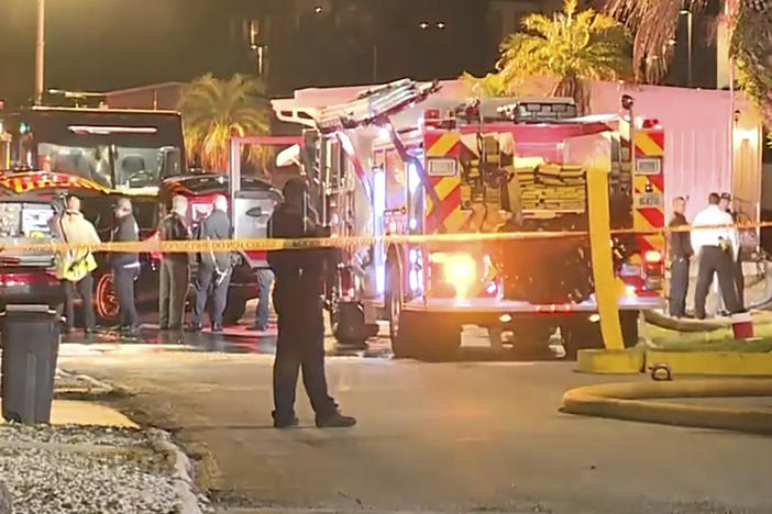 In this image made from video, a fire engine, firefighters and other officials are seen inside police tape on scene of a small plane crash in Clearwater, Florida, Feb. 1, 2024.
