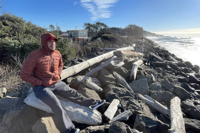 Ryan Hendricks, who is a member of the Quinault Tribal Council, sits on a driftwood log on the Taholah, Wash., sea wall. The coastal tribe is working to move its villages away from the rising waters of the Pacific Ocean and its tsunamis.