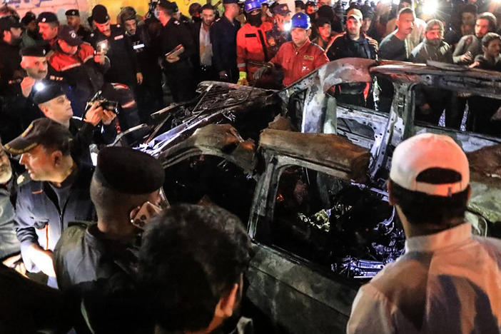 People, rescuers and security forces gather around a vehicle hit by a drone strike, reportedly killing three people, including two leaders of a pro-Iran group, in Baghdad on Wednesday.