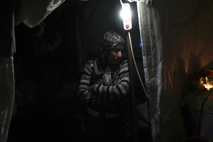 A woman stands next to a lamp inside a tent in Antakya, southern Turkey, on Jan. 12.