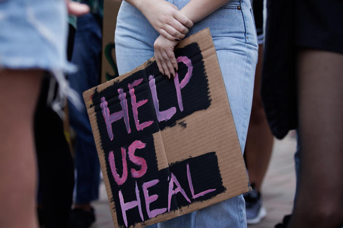 A student at Santa Clara University holds a sign in support of increased mental health services on campus, during a rally in the winter of 2021.