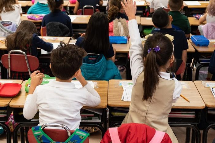 A second grader raises her hand in class at Nichols Hills Elementary School in Oklahoma City in 2020. Under a new bonus program aimed at addressing teacher shortages, over 500 educators received bonuses of up to $50,000.