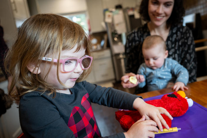Julia Cramer sits with her two children, Maya, 3, and Lily, 6 months, at their home in Petaluma, Calif., on Dec. 19. Maya uses a toy medical syringe on an Elmo doll that she often brings along to the doctor's office.