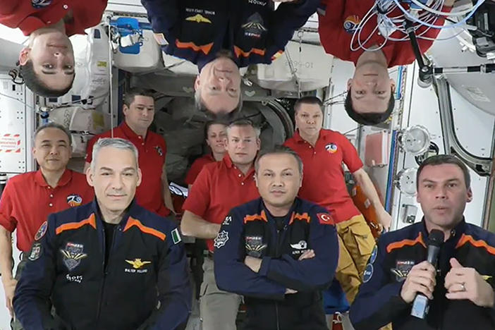 In this image from video provided by NASA, the 11 International Space Station crew members representing Expedition 70 (red shirts) and Axiom Space 3 (dark blue suits) crews gather for a farewell ceremony calling down to mission controllers on Earth on Friday, Feb. 2, 2024.