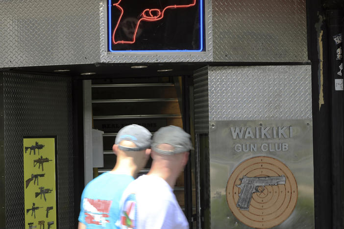 People walk past a gun club on June, 23, 2022, in Honolulu. A ruling by Hawaii's high court saying that a man can be prosecuted for carrying a gun in public without a permit uses pop culture references in an apparent rebuke of a U.S. Supreme Court decision that expanded gun rights nationwide.