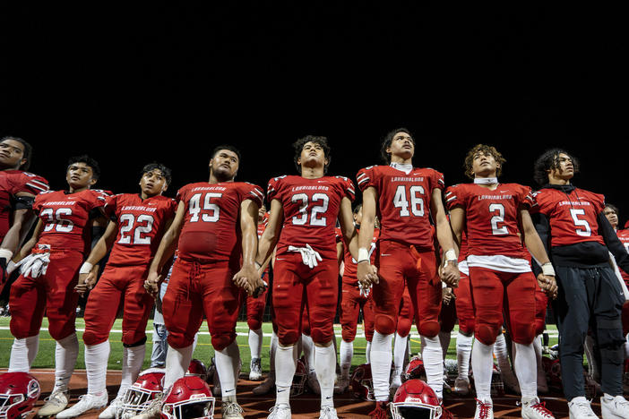 FILE - The Lahainaluna High School football team hold hands to thank the fans after a game on Oct. 21, 2023, in Lahaina, Hawaii. Captains of the team whose town was destroyed by a deadly wildfire attended to Super Bowl in Las Vegas as guests of the NFL.