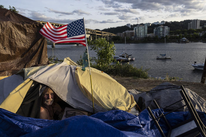 A man named Frank sits in his tent with a river view in Portland, Ore., in 2021. A lawsuit originally filed in 2018 on behalf of homeless people in the Oregon city of Grants Pass is set to go before the U.S. Supreme Court in April.