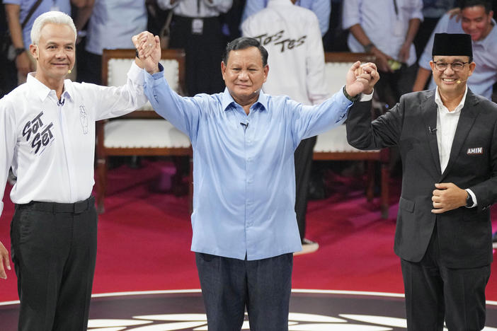 Presidential candidates from left, Ganjar Pranowo, Prabowo Subianto and Anies Baswedan hold hands as they pose for photographers after the first presidential candidates' debate in Jakarta, Indonesia, Dec. 12.