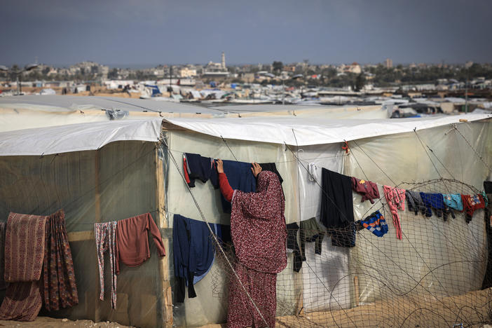 A displaced Palestinian woman hangs laundry to dry outside a tent at a makeshift camp on the Egyptian border, west of Rafah in the southern Gaza Strip on Jan. 14.