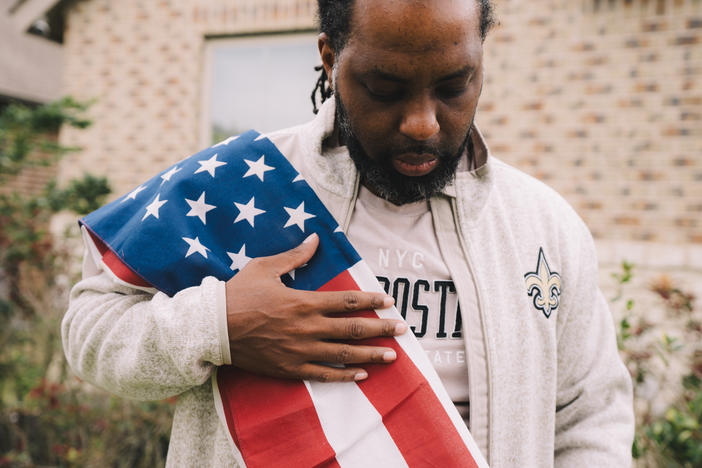 Edmund Garcia, an Iraq war veteran, holds the American flag over his shoulder outside his home on Thursday in Rosharon, Texas.